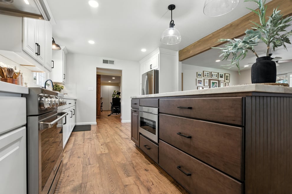 Clovis kitchen remodel with wood floor, white shaker perimeter cabinets, custom range hood, and walnut toned island with seating