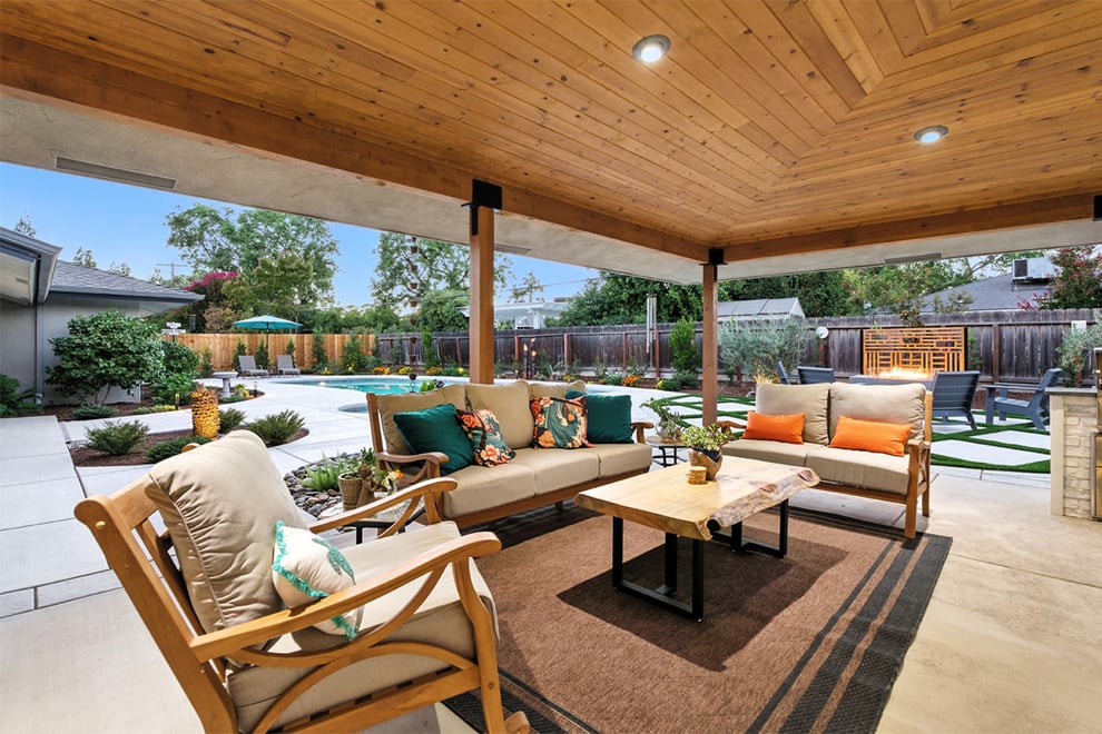 Covered patio seating area in Fresno, CA with wood ceiling and poolside landscaping