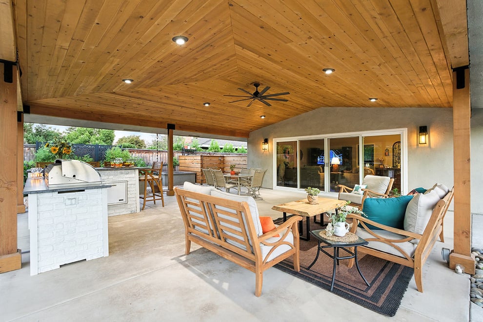 Covered patio with seating, grill, and ceiling fan in Fresno, CA backyard