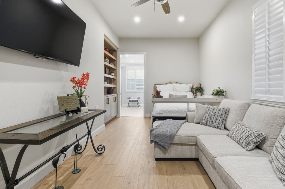 Cozy sitting room with TV, shelving, and a view into a connected bedroom and bathroom in Fresno