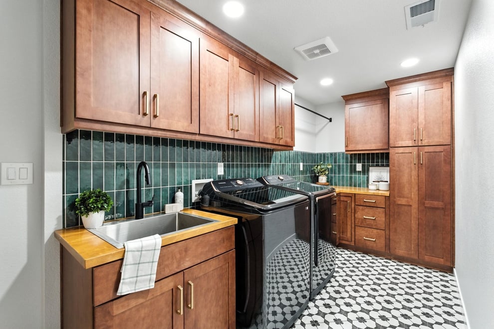 Fresno laundry room with wood cabinets, green tile backsplash, black appliances, and patterned floor