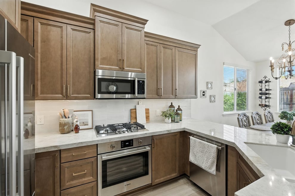 Modern kitchen with brown cabinets, stainless steel appliances, and marble countertops in Fresno, CA
