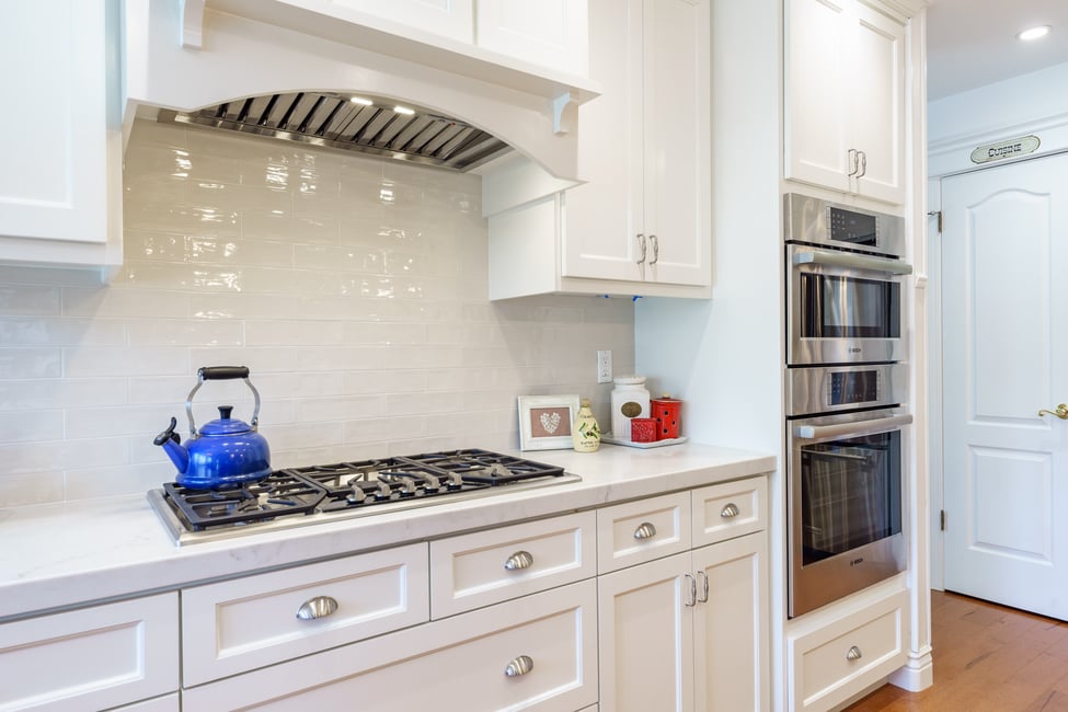 white kitchen by Imagine Remodeling with glossy white subway tile backsplash. double oven and range.