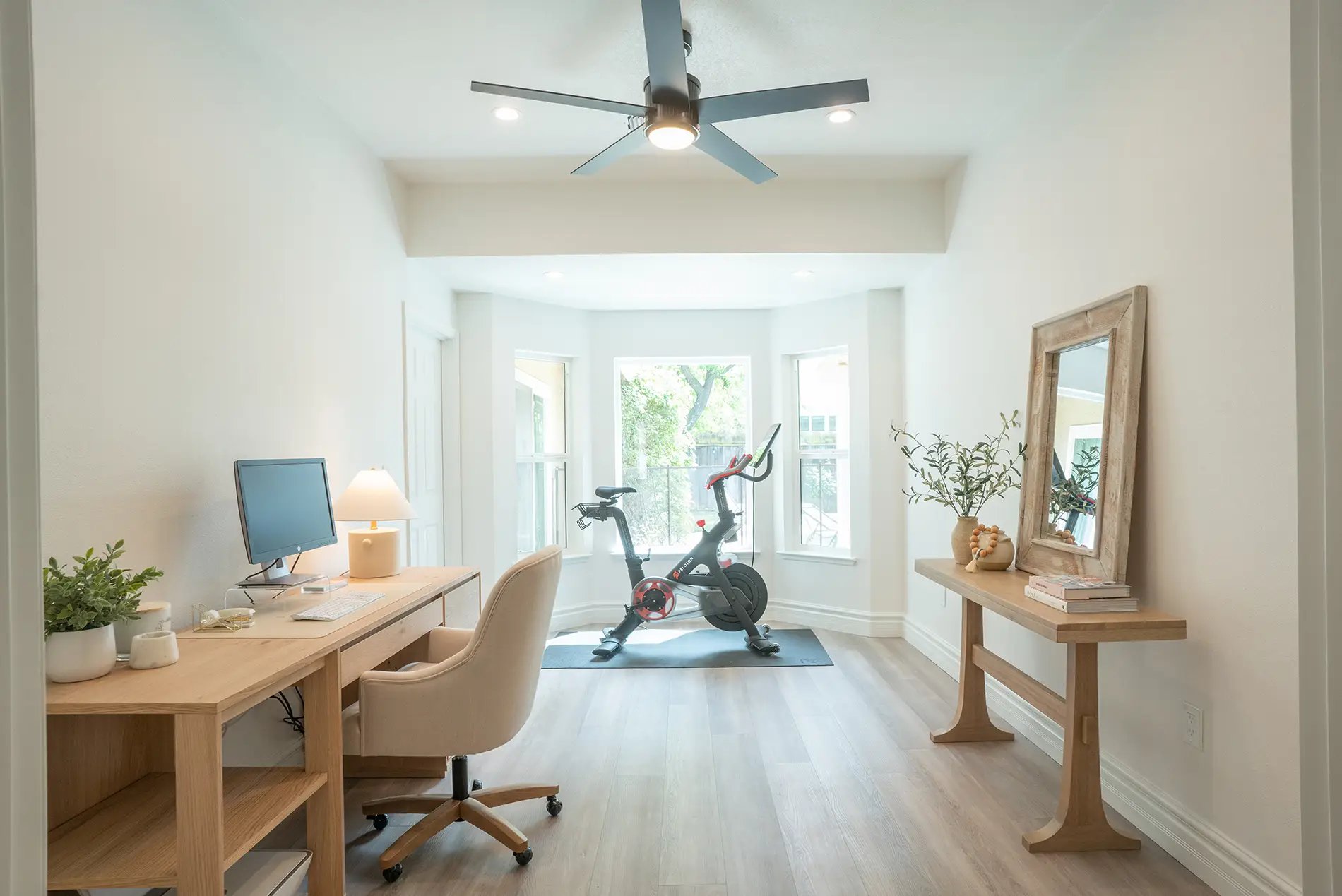 Sunny multi-purpose room with blonde oak floors, high ceilings, and office and workout space