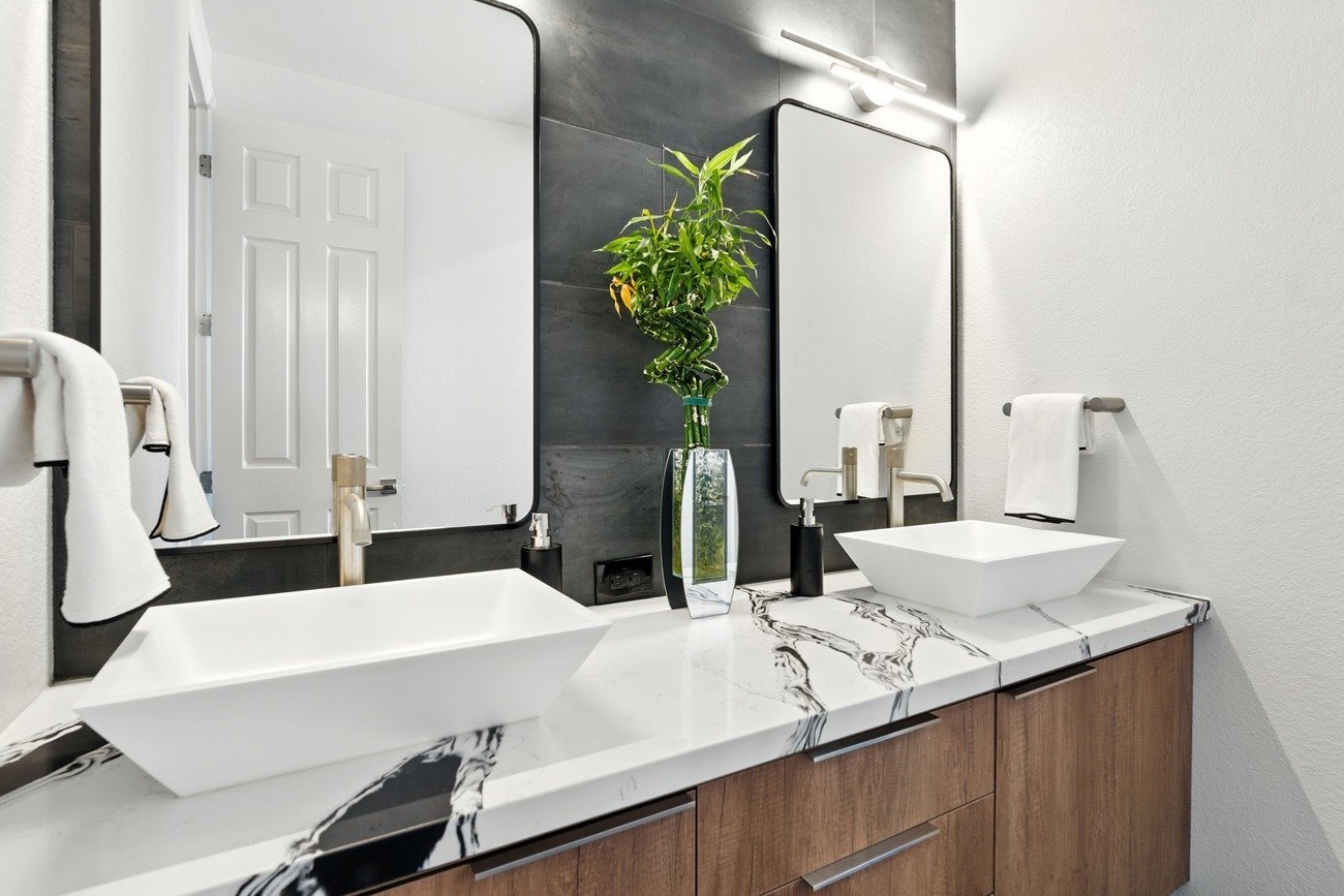Fresno bathroom with vessel sink, marble style counter, wood vanity, and modern mirror